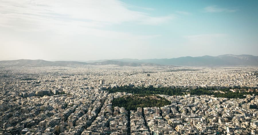 Aerial view of Athens cityscape showcasing urban density with mountains in the background.